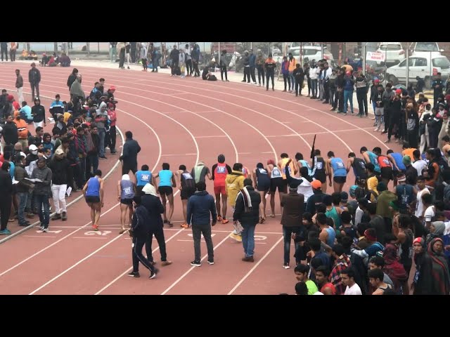 Track athletes running at full speed on a rubberized track with stadium in background